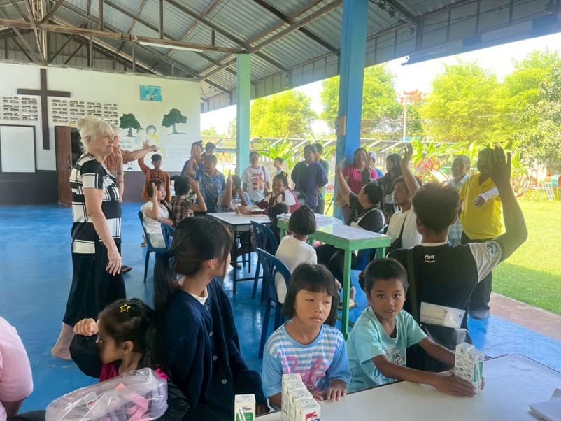 Sunday school in the dining hall at the home: kids at the tables, hands up